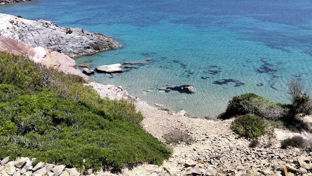 A coastal landscape with clear blue waters, rocky shores, and sparse vegetation. - Residenza Cala di Seta Appartamento trilocale Mario per 5 persone (Calasetta)