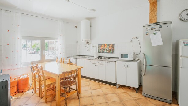 Eine Küche mit weißen Schränken, einem Holztisch und einem Kühlschrank.