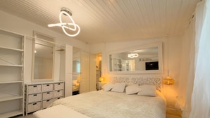 Une chambre à coucher avec un lit, un grand miroir, une armoire et une table de chevet.