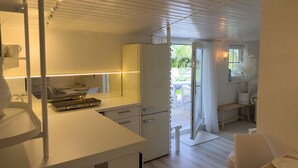 Une cuisine moderne avec des meubles blancs, un plan de travail et un coin repas comprenant une table et des chaises.