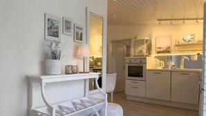 Une cuisine moderne avec des meubles blancs, un four encastré et un coin repas comprenant une table et des chaises blanches.