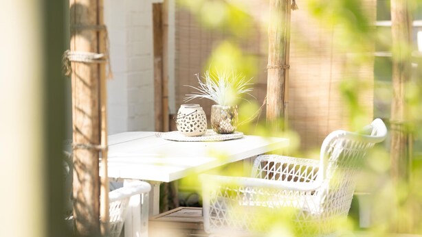 Une table avec deux chaises, un panier en osier et une plante en pot.