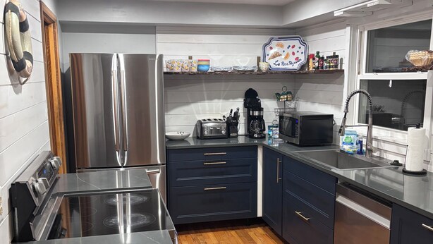 Una cocina moderna con electrodomésticos de acero inoxidable, armarios oscuros y piso de madera.