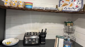Una cocina con tostadora, un bloque de cuchillos y una repisa con platos y cuencos.