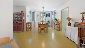 Une pièce spacieuse comprenant une table à manger, des chaises, un buffet et une grande fenêtre.