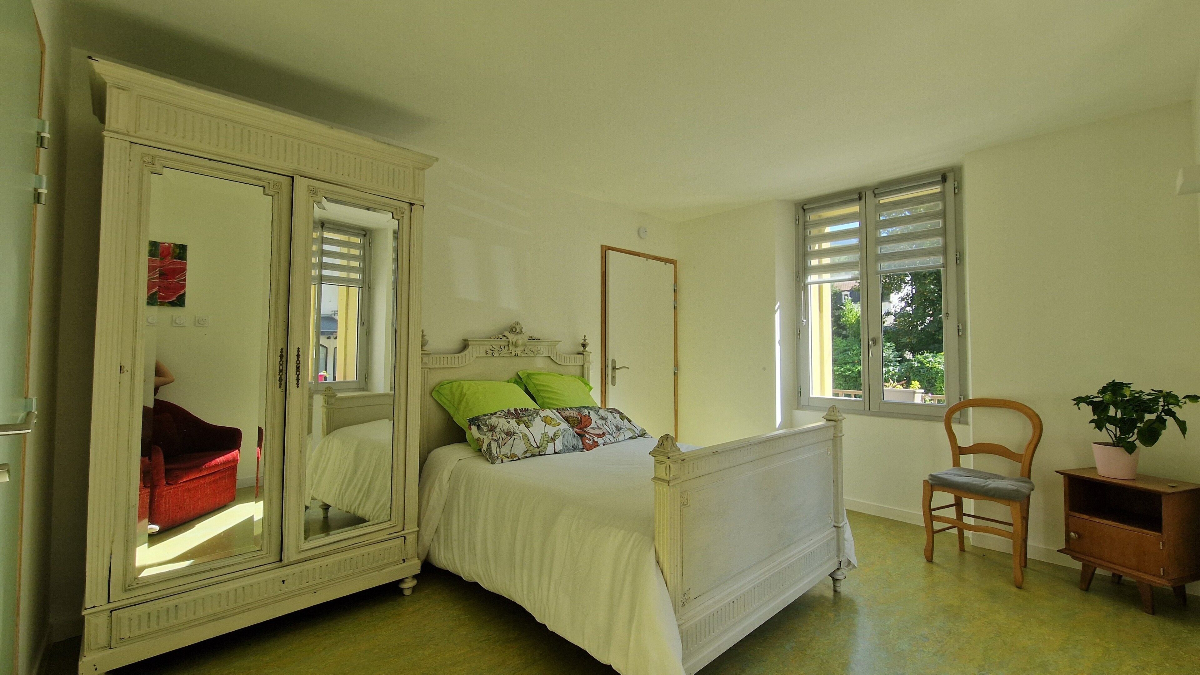 A bedroom with a bed, a wardrobe, a chair, and a window.