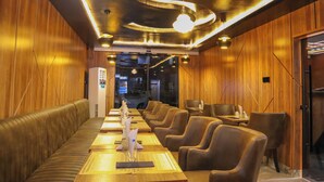 A restaurant with wooden walls, leather booths, and a long dining table with chairs. - Victoria Plus Hotel & Suites (Asaba)