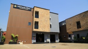 A modern building with a sign for 'Victoria Plus Hotel & Suites.' - Victoria Plus Hotel & Suites (Asaba)