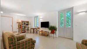 A living room with a sofa, a television, a bookshelf, and a potted plant. - Room 5 – Le Toit Vert Inn: Space and Shared Moments in Moutiers (Moûtiers)
