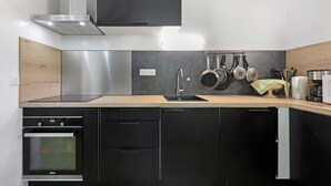 A modern kitchen with a built-in oven, a stainless steel range hood, and a wooden countertop. - Room 5 – Le Toit Vert Inn: Space and Shared Moments in Moutiers (Moûtiers)