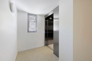 A narrow hallway with a window, a door, and a metallic elevator. - Room 4 – L’Auberge Le Toit Vert: Space and Sharing in Moutiers (Moûtiers)