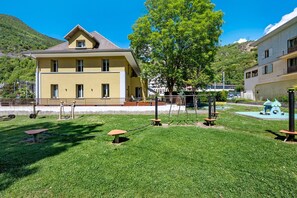 A residential building with a flat roof, a balcony, and a well-maintained lawn with playground equipment. - Room 4 – L’Auberge Le Toit Vert: Space and Sharing in Moutiers (Moûtiers)
