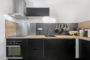 Una cocina moderna con horno empotrado, extractor de acero inoxidable y encimera de madera.