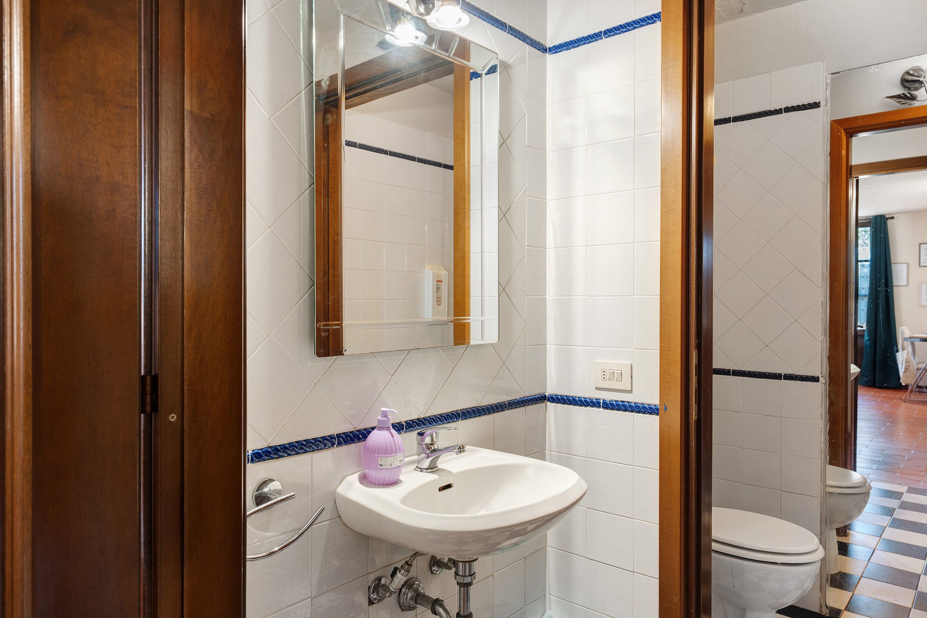 Une salle de bain avec un lavabo blanc, un miroir et des toilettes.