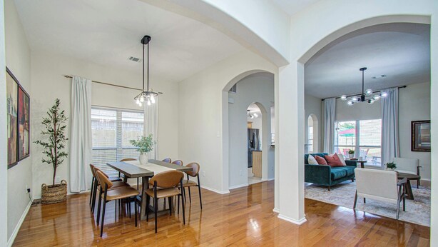 A spacious living area with hardwood flooring, a dining table with chairs, a sofa, and a chandelier. - 4BR Game Room + Firepit Sleeps 9 Near Eats (Houston)