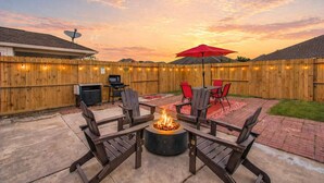 A backyard with a fire pit, outdoor furniture, and a wooden fence. - 4BR Game Room + Firepit Sleeps 9 Near Eats (Houston)