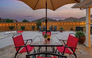 Eine Terrasse im Freien mit Tisch, Stühlen, einem Feuerkorb und Lichterketten.