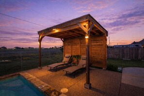 A wooden outdoor structure with a covered patio, two lounge chairs, and a swimming pool. - Heart of Ferris: 3-bd/2-ba With Pool, Patio & BBQ (Ferris)
