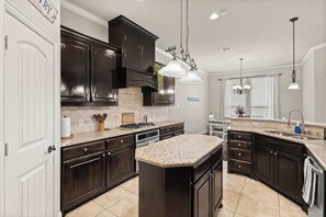 A kitchen with dark wood cabinets, a granite countertop island, and pendant lighting. - Heart of Ferris: 3-bd/2-ba With Pool, Patio & BBQ (Ferris)