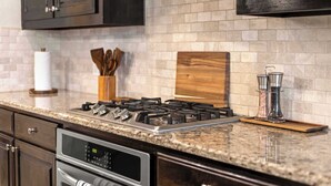 A kitchen with a gas stove, stainless steel appliances, and a brick backsplash. - Heart of Ferris: 3-bd/2-ba With Pool, Patio & BBQ (Ferris)