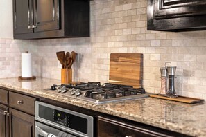 A kitchen with a gas stove, stainless steel appliances, and a brick backsplash. - Heart of Ferris: 3-bd/2-ba With Pool, Patio & BBQ (Ferris)