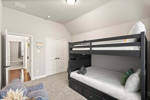A room with a bunk bed, a door, a hallway, and a carpeted floor. - Heart of Ferris: 3-bd/2-ba With Pool, Patio & BBQ (Ferris)