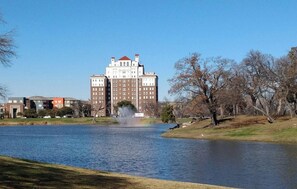 A large building with multiple floors and a central tower, a body of water with a fountain, and a grassy area with leafless trees. - Heart of Ferris: 3-bd/2-ba With Pool, Patio & BBQ (Ferris)
