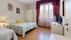 Un dormitorio con cama, mesita de noche, lámpara y ventana con cortinas.