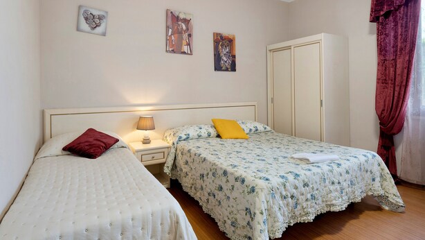 Un dormitorio con dos camas individuales, una mesita de noche con lámpara y un armario.