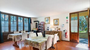 Un comedor con una mesa dispuesta para cuatro personas, un armario de madera y un extintor.