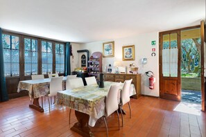Un comedor con una mesa dispuesta para cuatro personas, un armario de madera y un extintor.