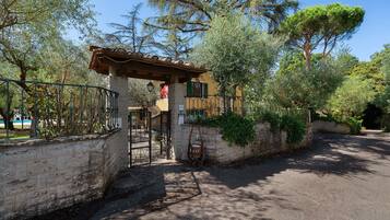 A gated entrance with a stone wall, a metal gate, and a pergola structure.