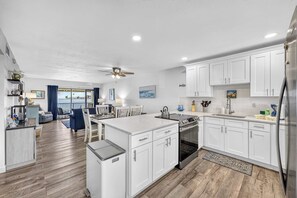 A modern kitchen with white cabinetry, a central island, and a view to the outside. - Bayfront • Rehabbed • Pickleball • Private Beach (Bradenton Beach)
