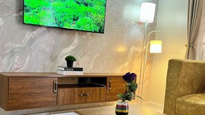 Una sala de estar moderna con televisor de pantalla plana, una mesita de centro, un sofá, un aparador y una lámpara de pie.