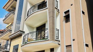 Un edificio residencial de varios pisos con balcones, entrada con portón y camino de acceso pavimentado.