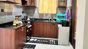 Una cocina compacta con armarios de madera, un lavamanos, una estufa y un refrigerador.