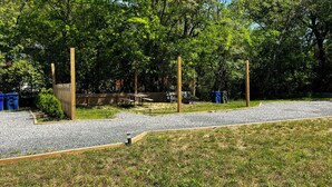 Un parco con tavoli da picnic, una recinzione in legno e cestini blu.