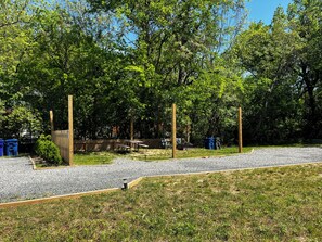 Ein Park mit Picknicktischen, einem Holzzaun und blauen Mülleimern.