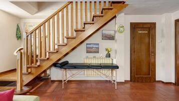 A wooden staircase with a handrail, a bench at the bottom, a radiator, and a door with a coat hook.