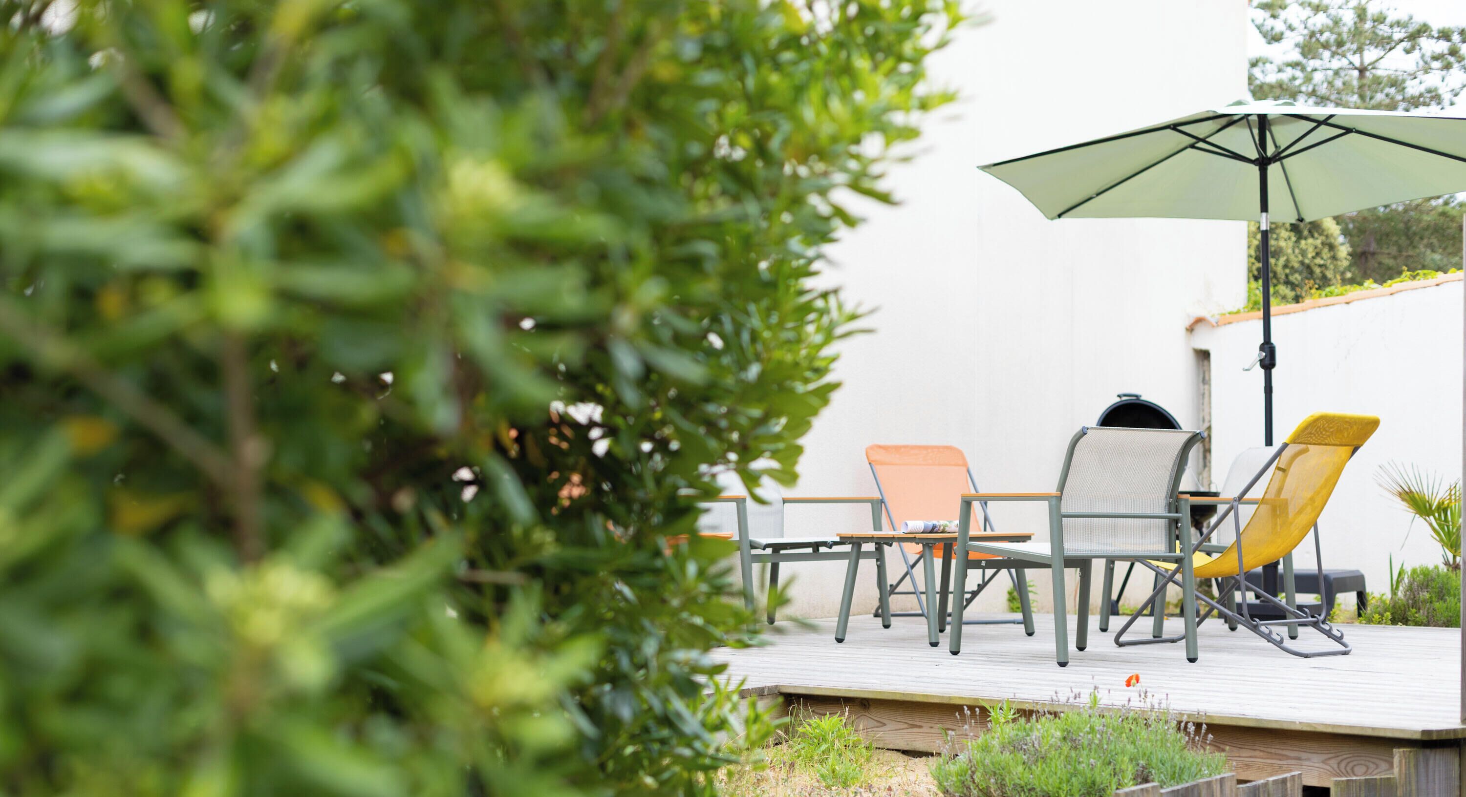 An outdoor patio with a table and chairs, a grill, and an umbrella.