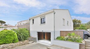 Ein modernes, zweistöckiges Haus mit Garage, Steinmauer und einer Holzterrasse.