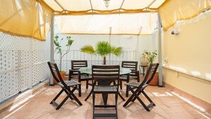 Un patio couvert avec une table et des chaises, des plantes en pot et une lanterne décorative.
