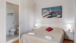 Hotellihuone, jossa on sänky, taulu, kylpyhuone ja yöpöytä.