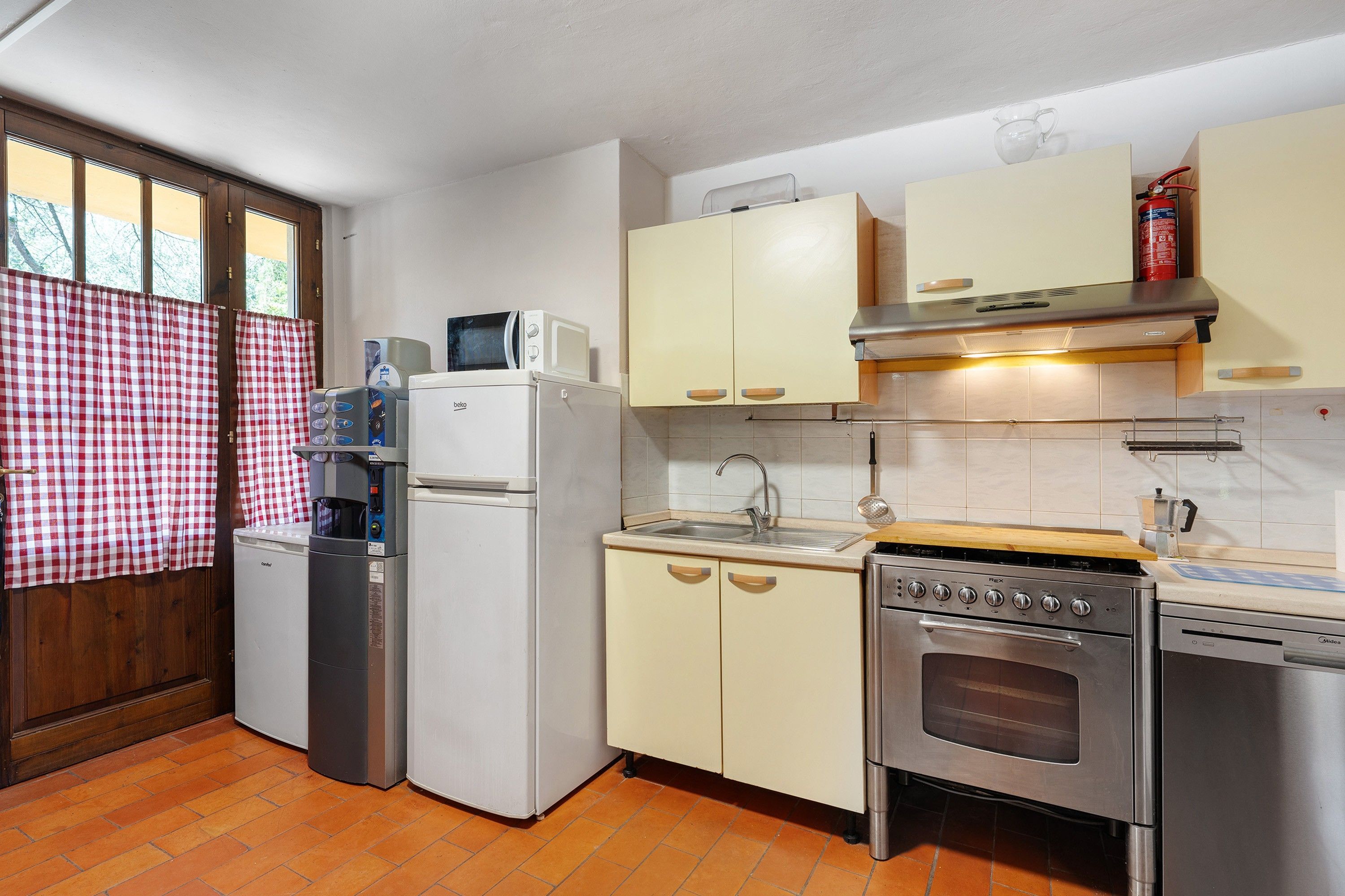 Una cucina compatta con frigorifero, microonde, lavello e fornello.