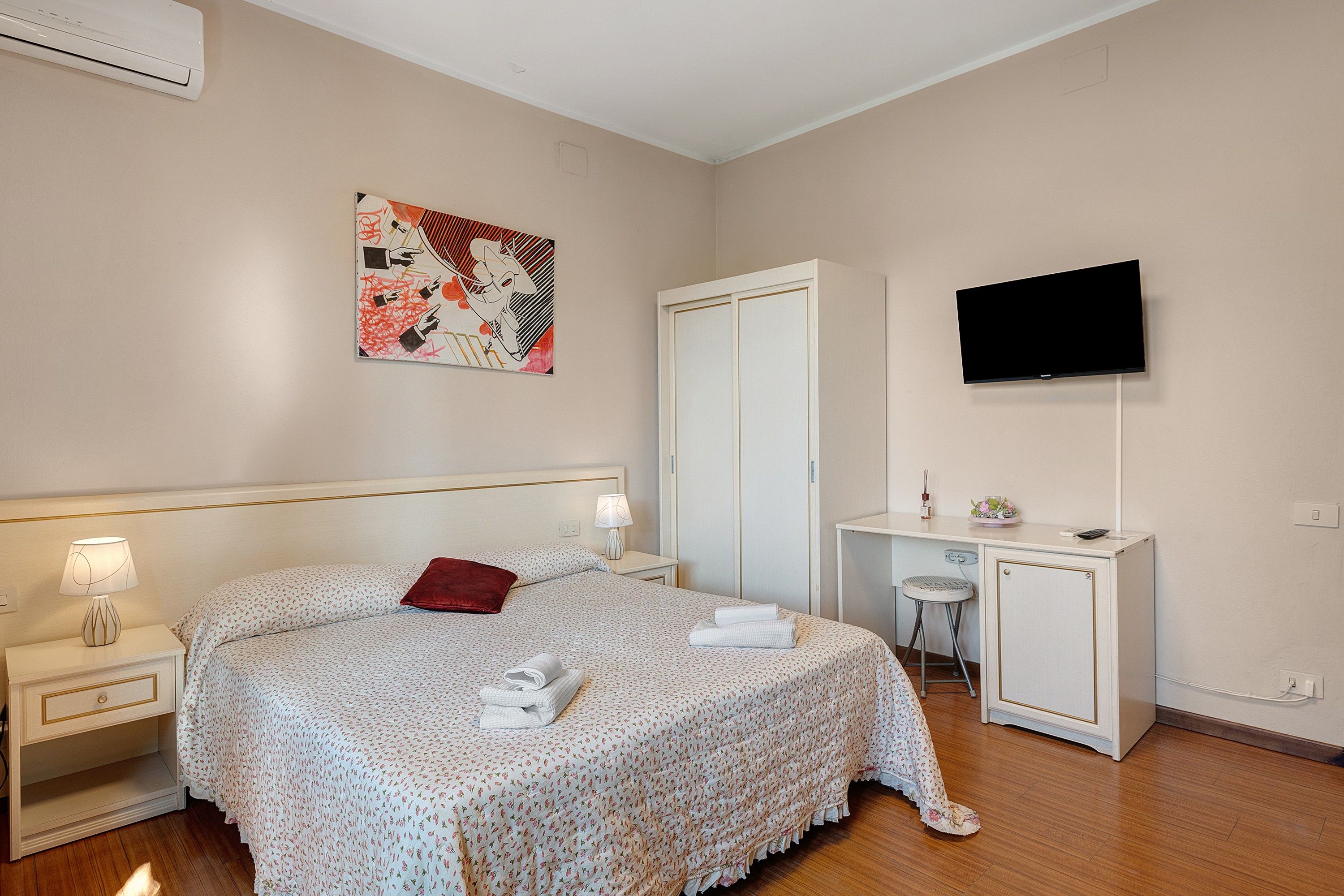 Une chambre d’hôtel comprenant un lit, des tables de chevet, un bureau, une télévision et une armoire.