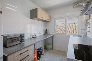 A modern kitchen with a built-in microwave, a coffee maker, and a window with a view of a tiled area. - Vacation Home 'Pisito De Pueblo II' with Mountain View, Wi-Fi, and Air Conditioning (Navaluenga)