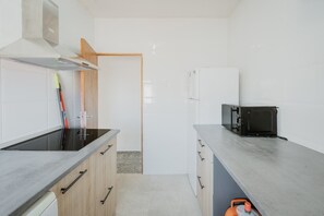 A modern kitchen with a black induction cooktop, a microwave, and a gas stove. - Vacation Home 'Pisito De Pueblo II' with Mountain View, Wi-Fi, and Air Conditioning (Navaluenga)