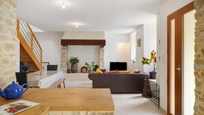 A living room with a sofa, a wooden table, a blue teapot, a fireplace, and a staircase.