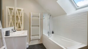 Une salle de bain avec une baignoire, une douche, des toilettes, un lavabo et une fenêtre.