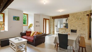A modern living room with a sofa, coffee table, and dining area with chairs and a table.